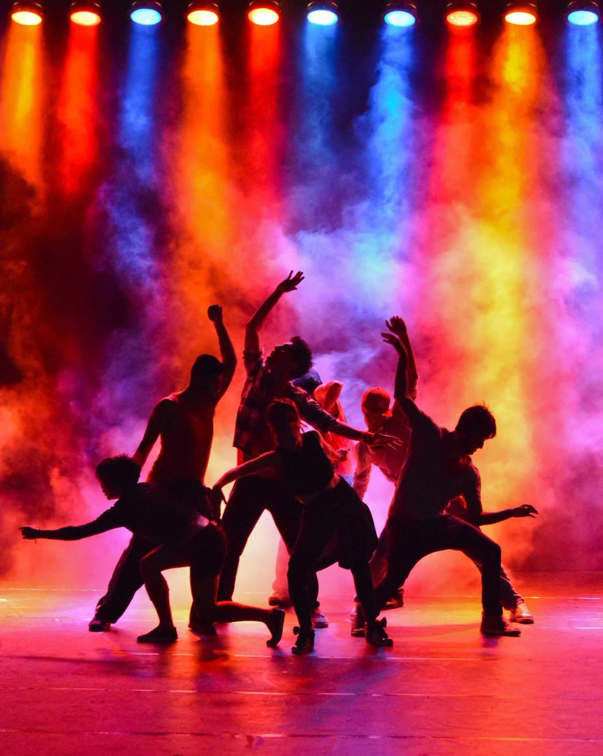 Dance crew performing on stage under colored lights